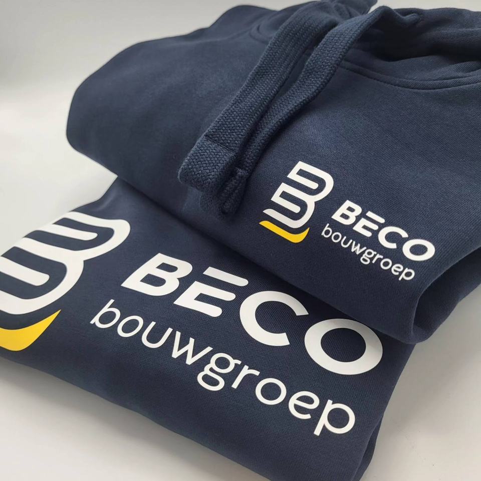 Opgevouwen werkkledij in marineblauw met het logo van Beco Bouwgroep erop