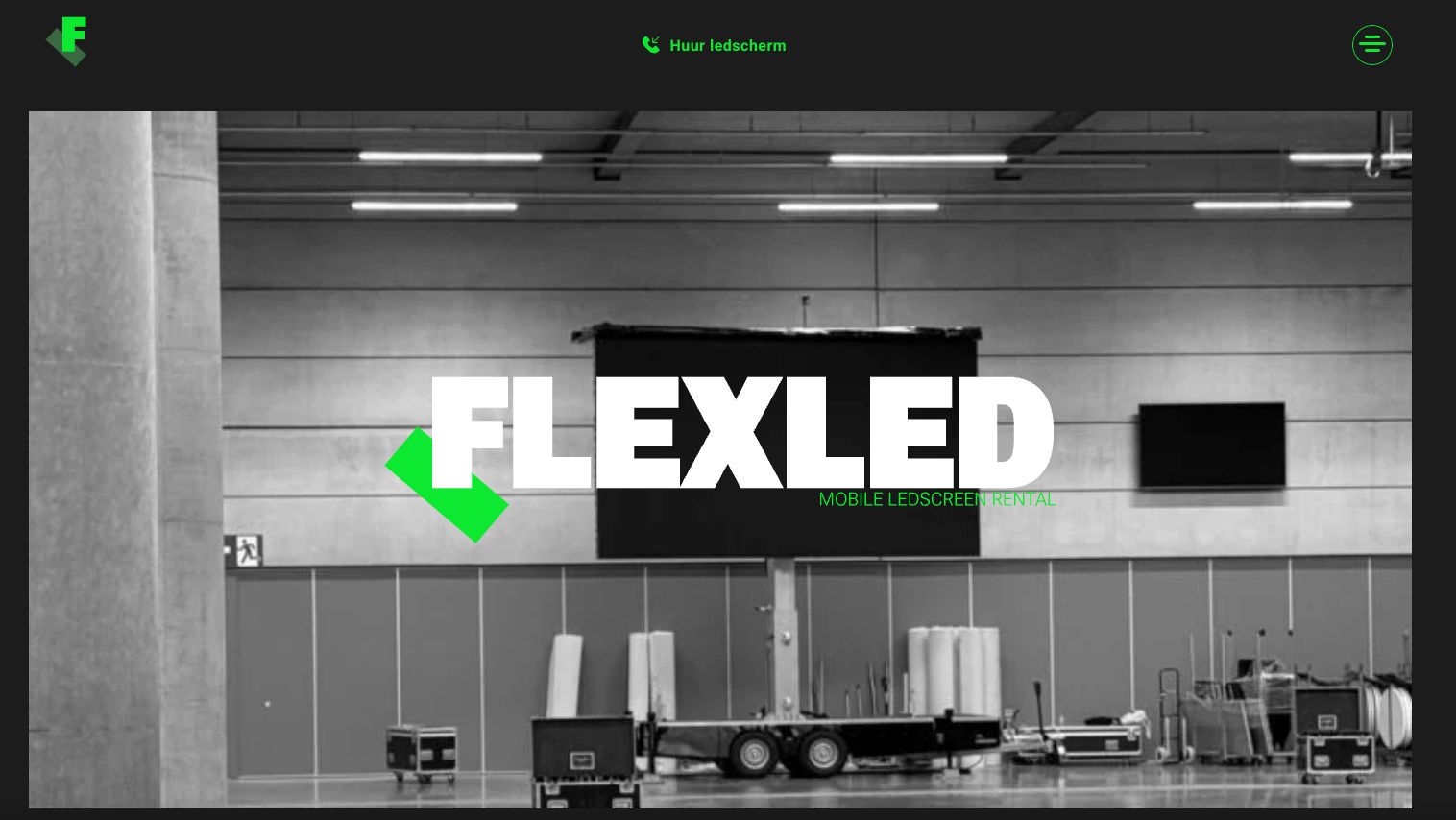 Flexled-logo op een groot scherm in een industriële ruimte met apparatuur en wanden op de achtergrond.