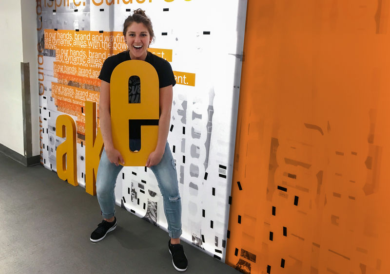 An enthusiastic woman holding a large Ethos dimensional letter