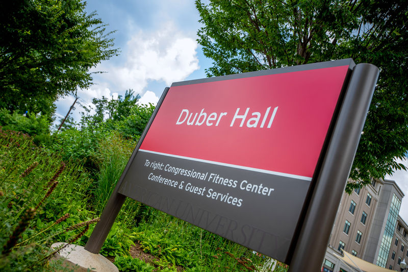 A post and panel double-sided exterior wayfinding sign installed outside a collage facility