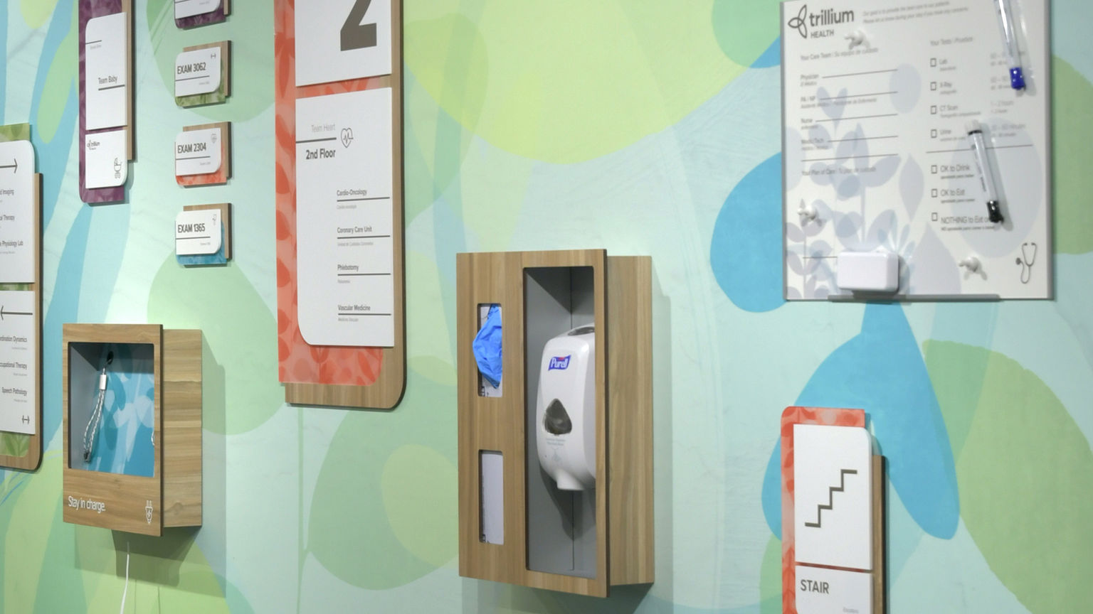 Healthcare wall accessories, including sanitizer station, charging station, and message board, with finishes and graphics that integrate with signage and wayfinding system.