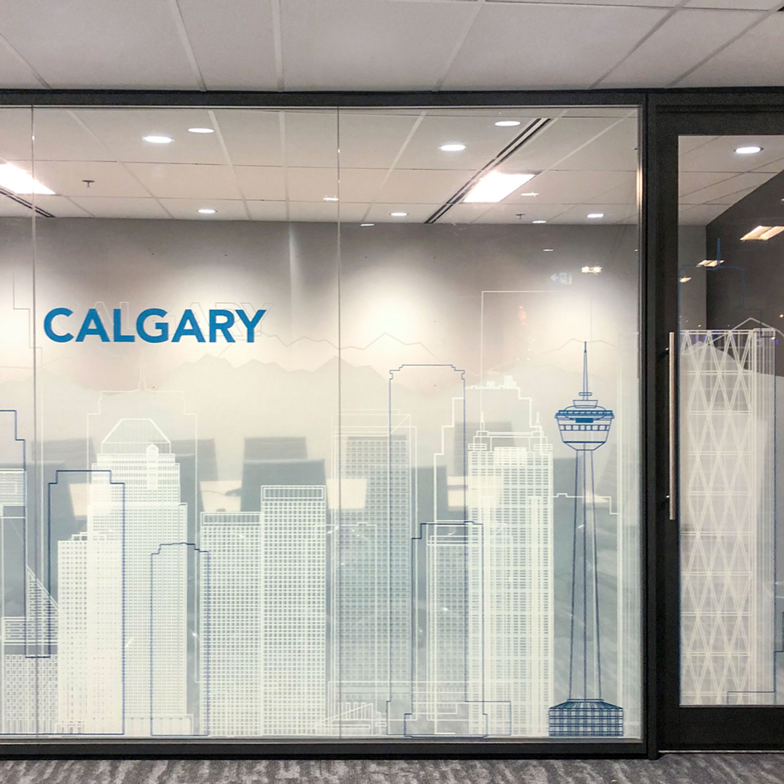 Privacy window film with the Calgary city skyline graphics spans a conference room's glass walls and doors.