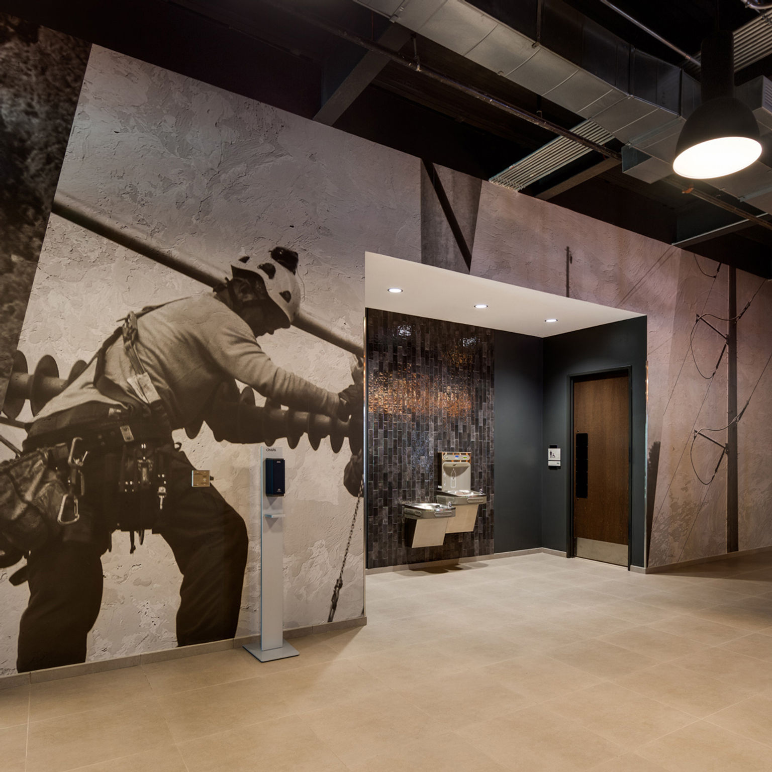 Custom self-adhesive wall covering installation featuring an oversized dramatic image of an electric utility technician working on a powerline.