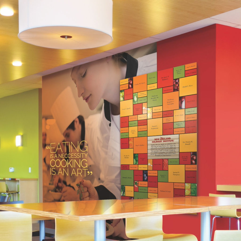 A colorful recognition display design for a culinary school featuring replaceable magnetic tiles; the display is integrated with a custom wallcovering installation featuring working culinary students