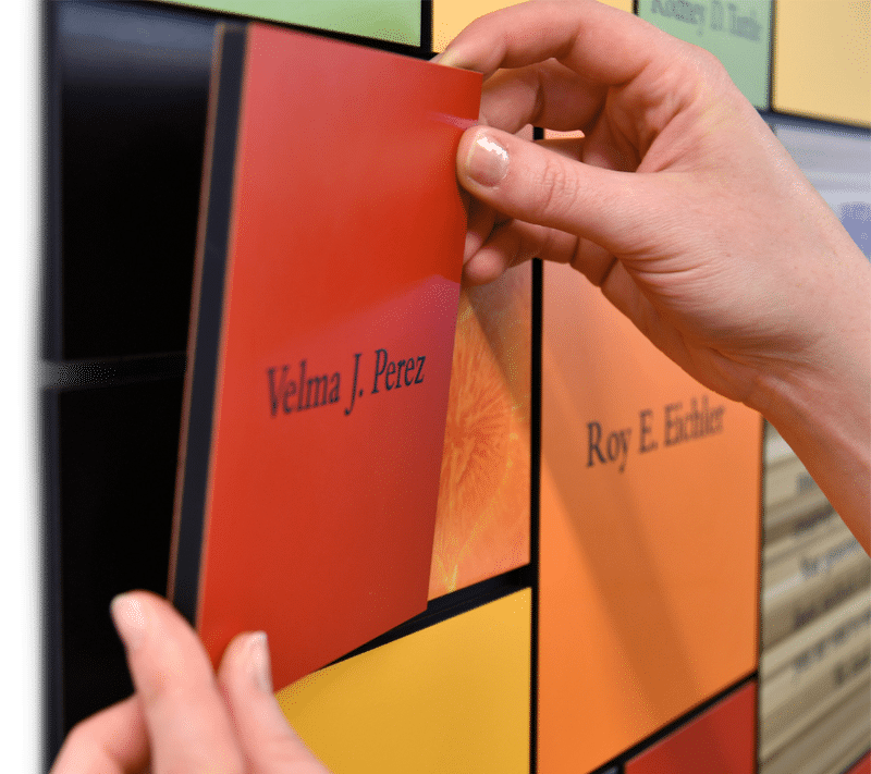 Close up perspective of a red magnetic plaque being removed from a culinary institute donor recognition display