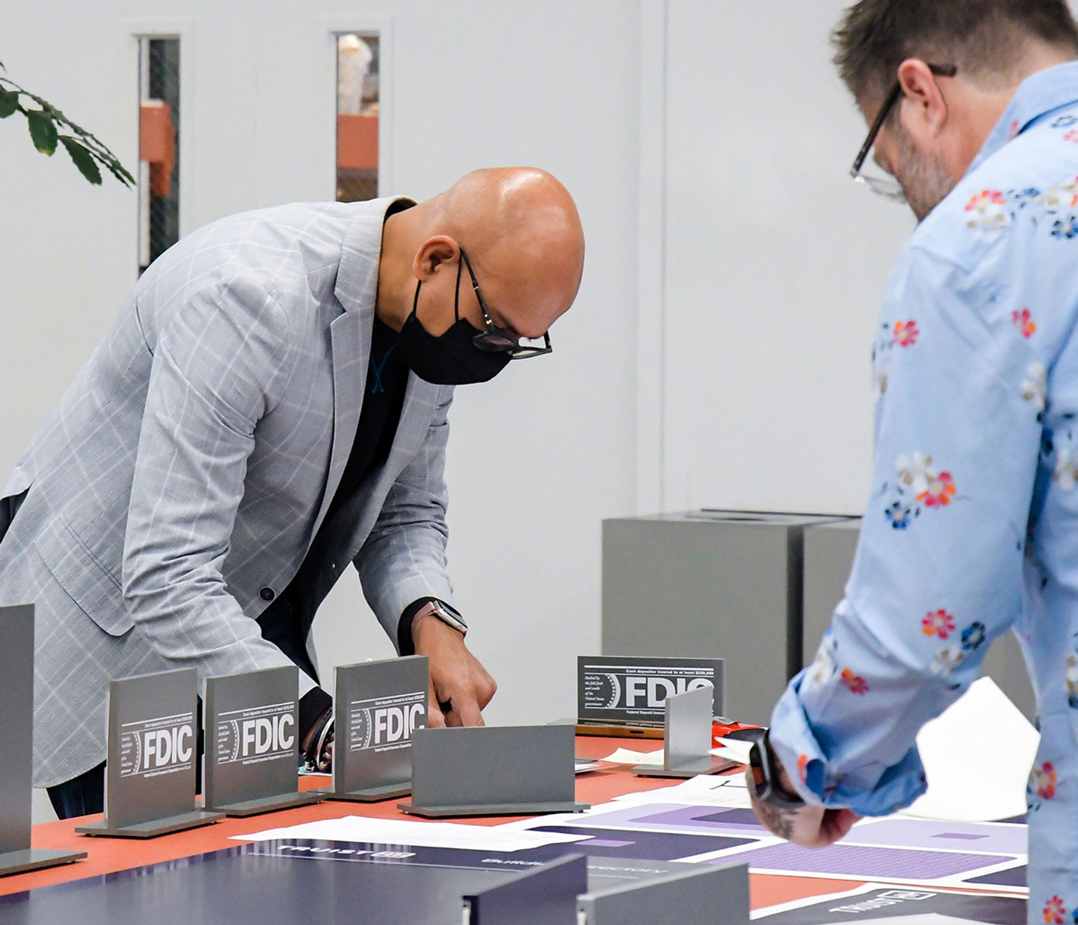 Two men reviewing interior bank teller signage samples.