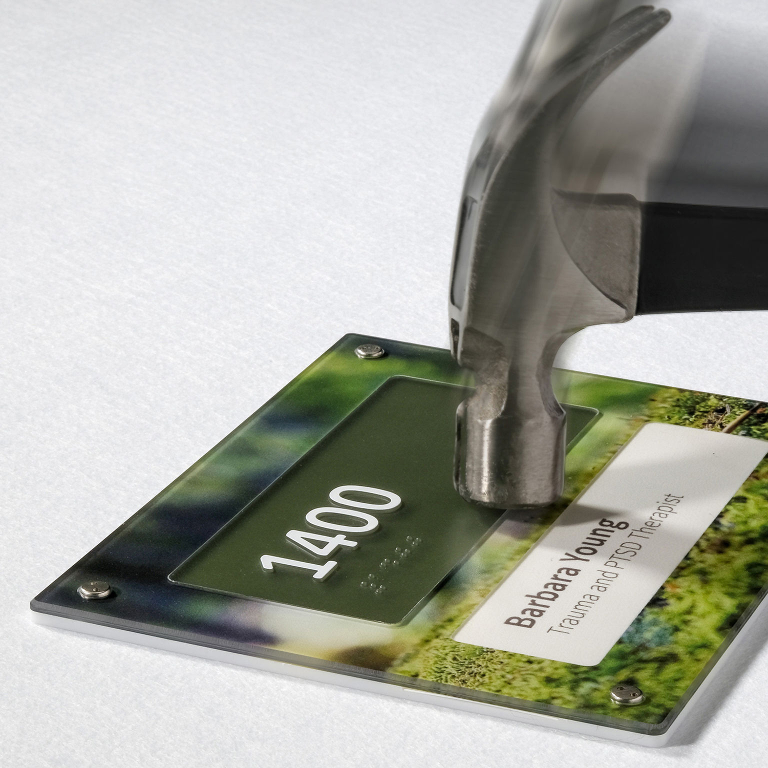 A motion photo of a claw hammer striking the face of an Empath unbreakable polycarbonate sign.