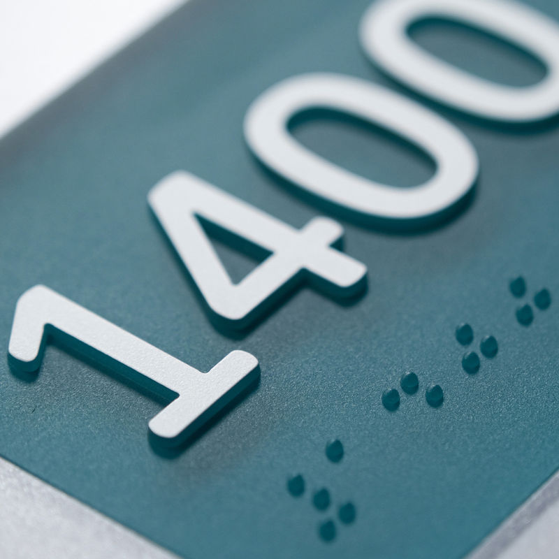 Detail of one-piece ablated raised letters and Braille on an Empath room ID sign.