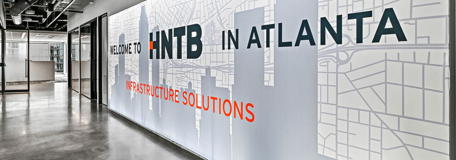 A photo of an wall-to-wall illuminated silicone edge graphic with a custom printed graphic over an Atlanta skyline line drawing.