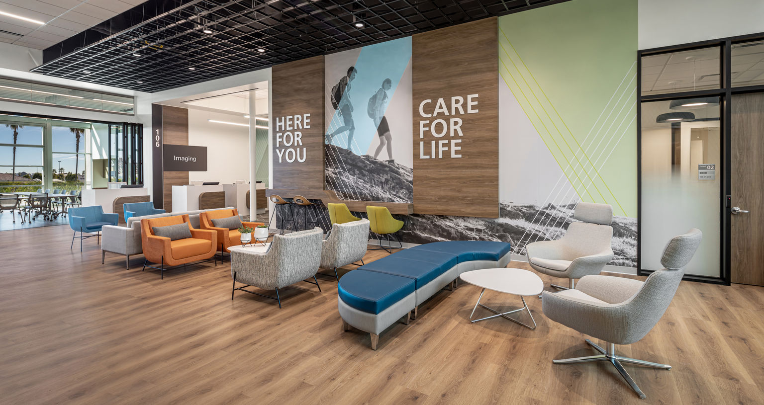 A contemporary hospitality-inspired healthcare lobby design with experiential graphics and signage. Custom wallcovering features features scenes of active hikers in local terrain.