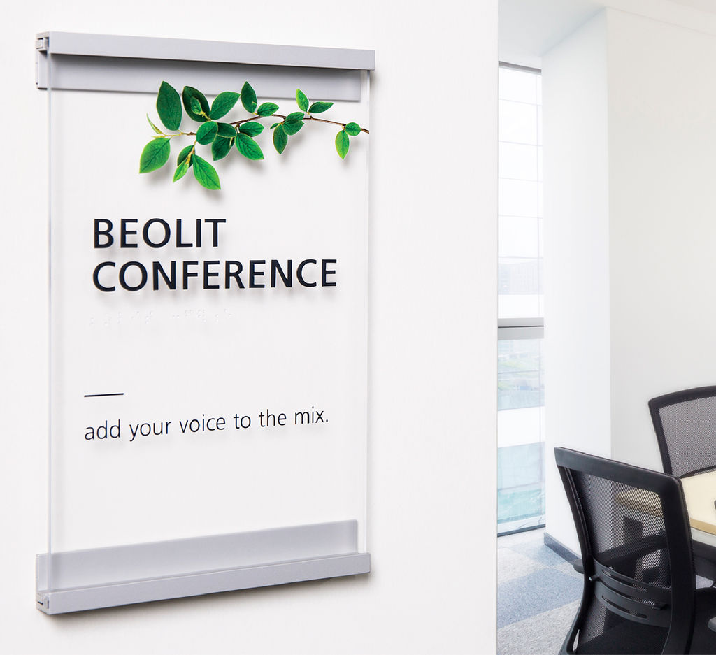 Minimalist metal and glass-look custom conference room ADA sign with a plant-themed design adjacent to doorway
