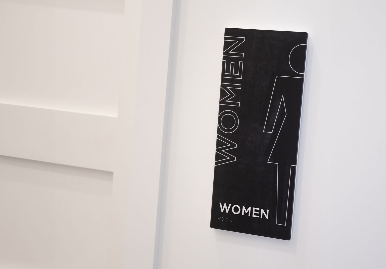 An ADA compliant woman's restroom sign of minimalist design and fabricated from Vivid image intense interior signage family.