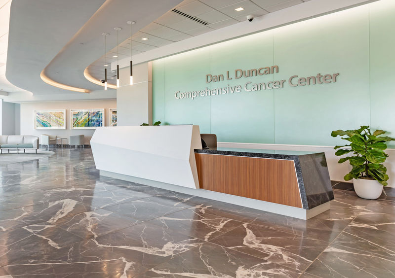 A medical center lobby with beautiful stone flooring adorned by Ethos dimensional letters installed on glass above the desk.