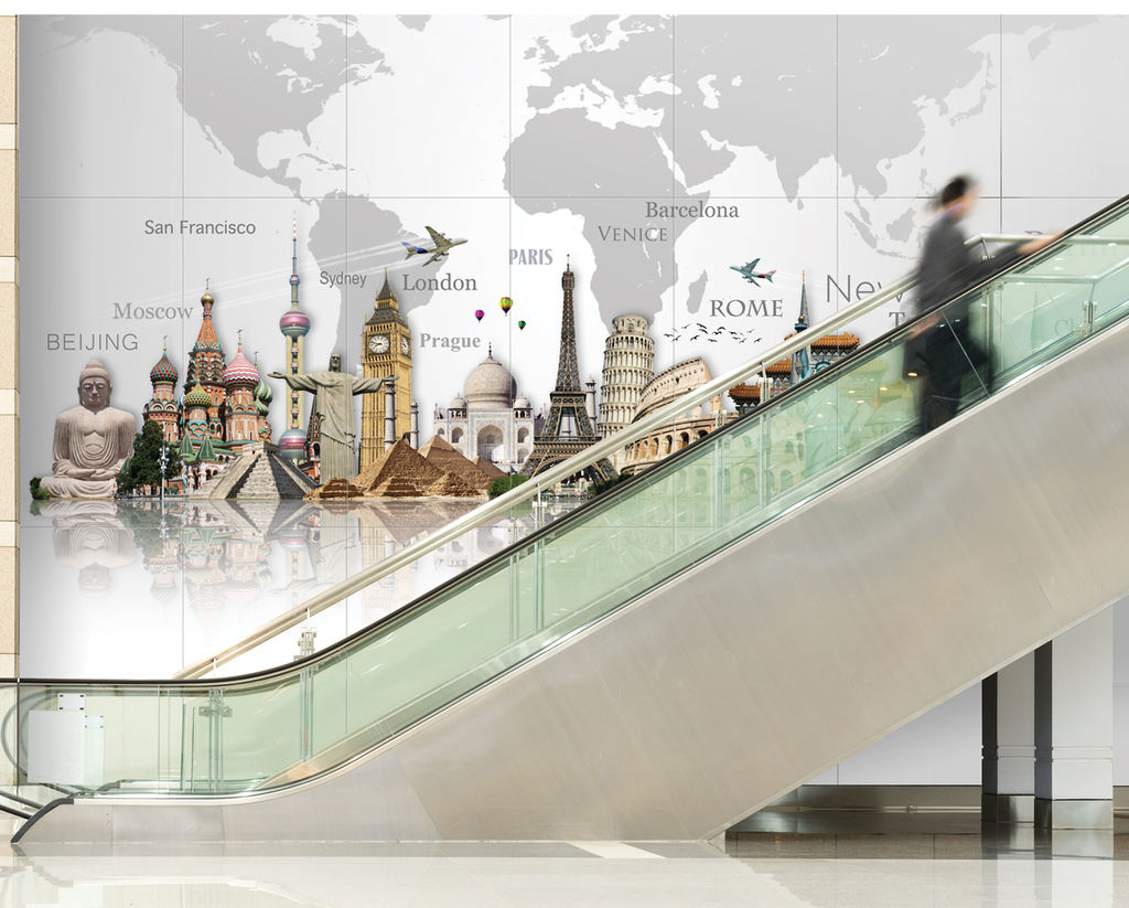 An expansive experiential graphic display in an airport featuring international architectural landmarks and a world map on a multi-story graphic panel installation