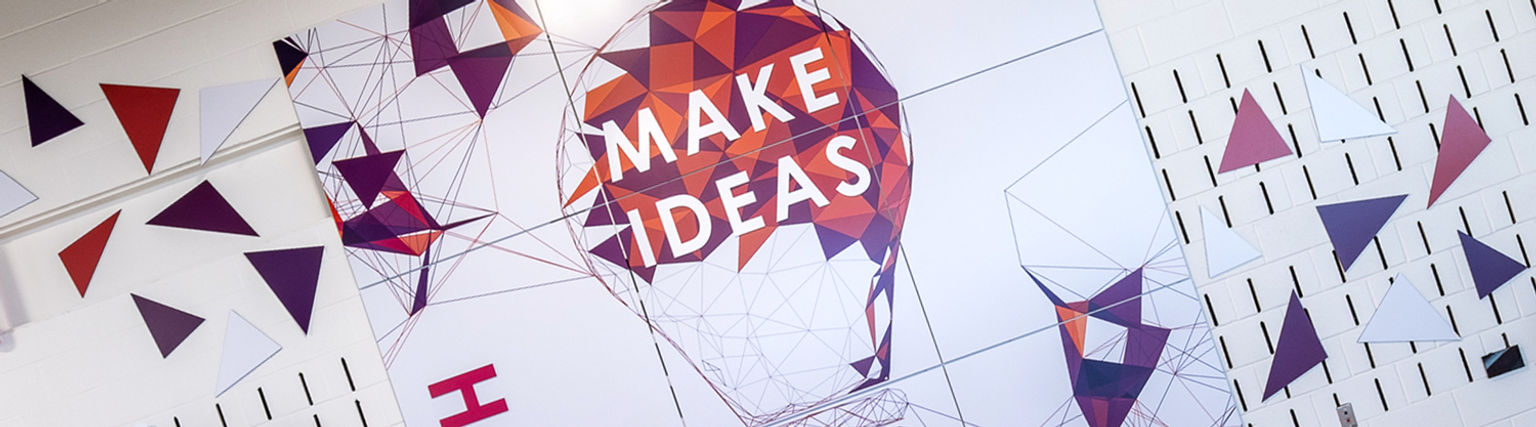 A visually energetic "Make Ideas" graphic panel installation in a professional school maker's space.