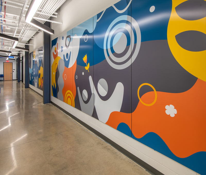 Colorful graphic panel installation with energetic, optimistic graphics spanning the length of the main corridor in a community recreation center