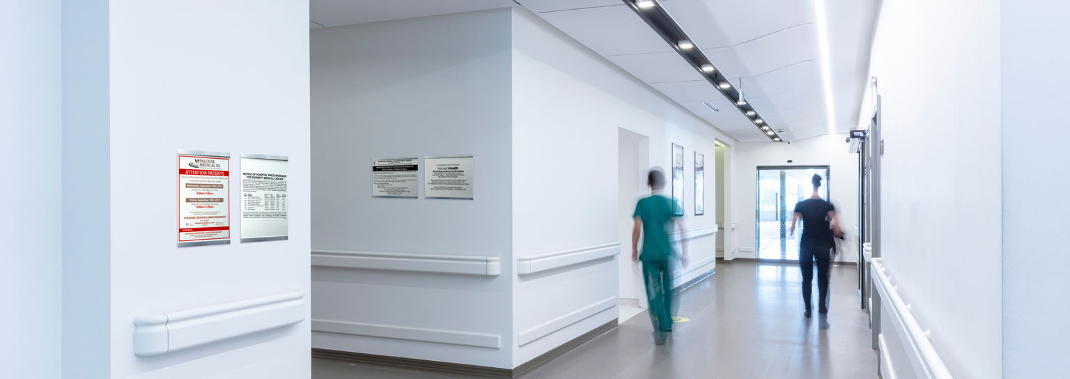 A busy hospital corridor with multiple notice holders hanging from the walls.