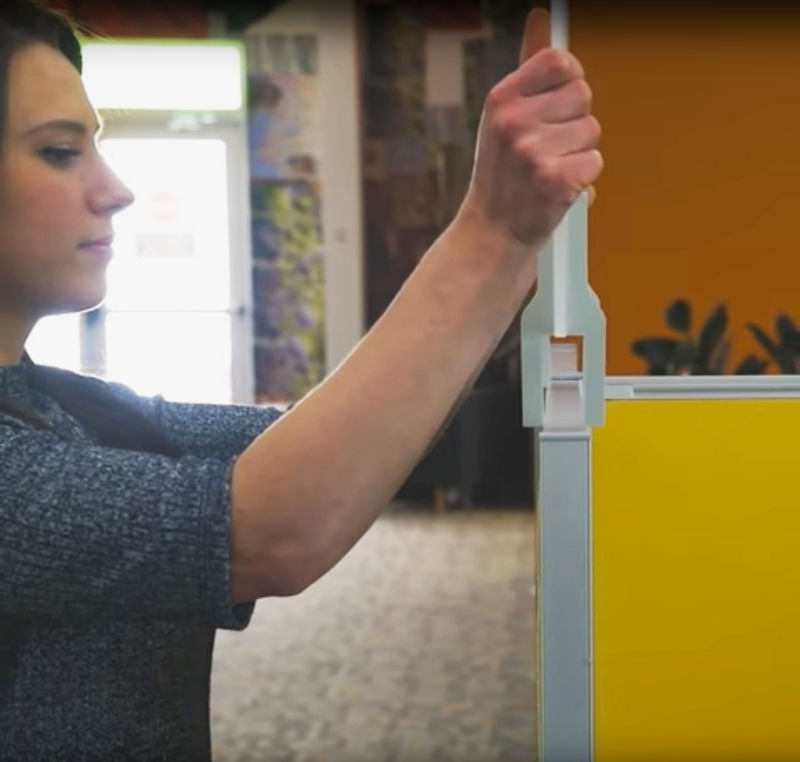 A young womanomph installs an Oomph acoustic workstation stacker by just sliding it on. No tools or fasteners.