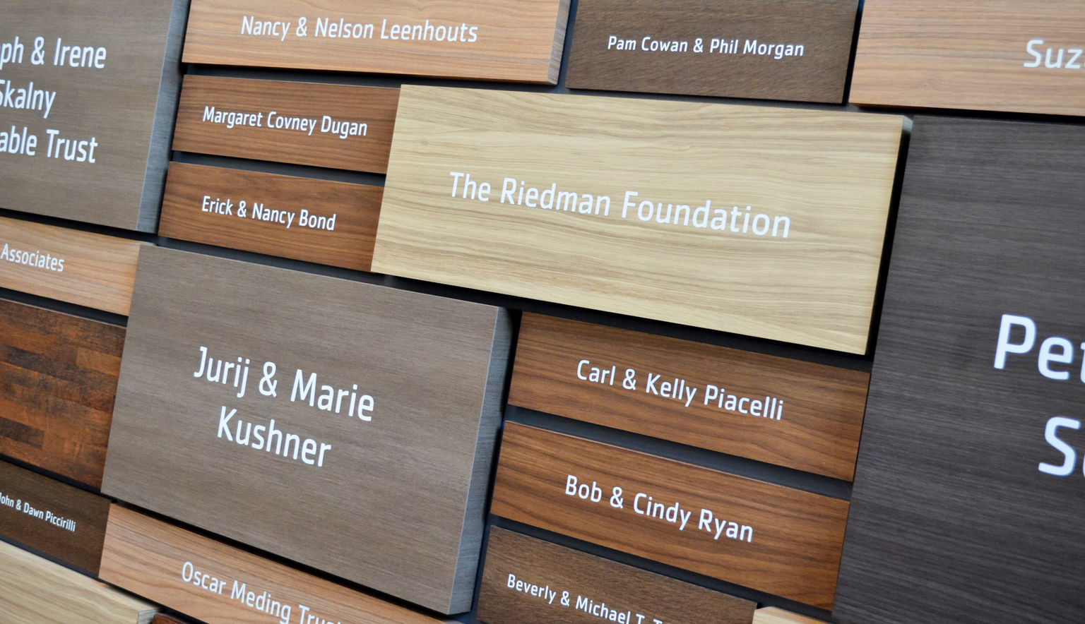 A close-up image of a large, elegantly-designed recognition display featuring rich wood-grain plaques of various sizes and woods..