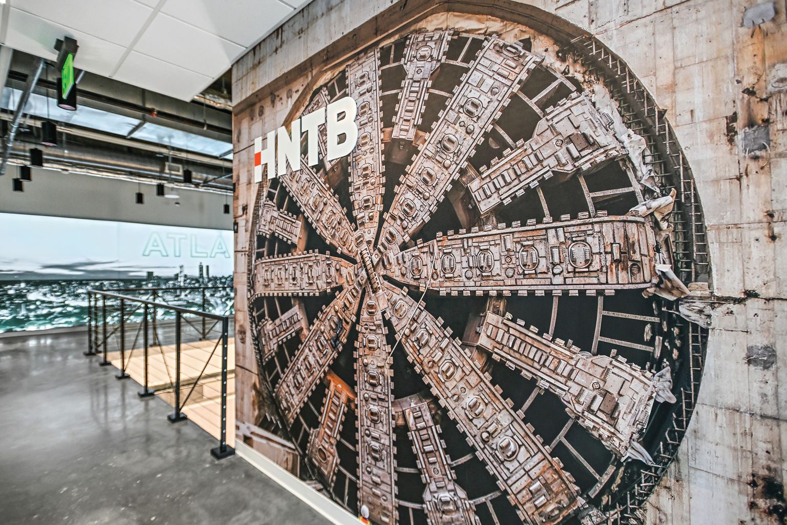 A large wallcovering with printed photo of a tunnel boring machine installed in a workplace setting.