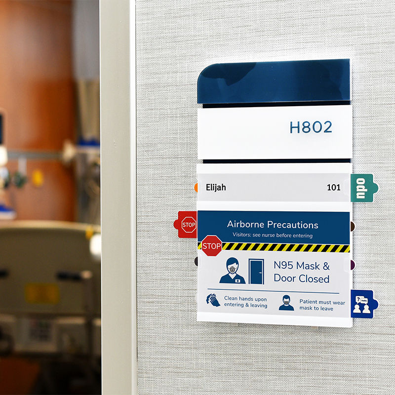 ADA-compliant nurse-alert patient room sign with tamper-resistant alert tabs and replaceable insert designed and fabricated to meet the hospital's sign standard.
