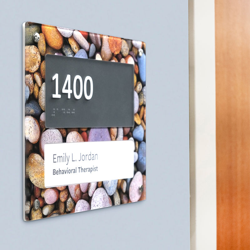 An ADA compliant room ID sign outside a Behavioral Health Therapist's office with a second surface print of a calming river rock photo.