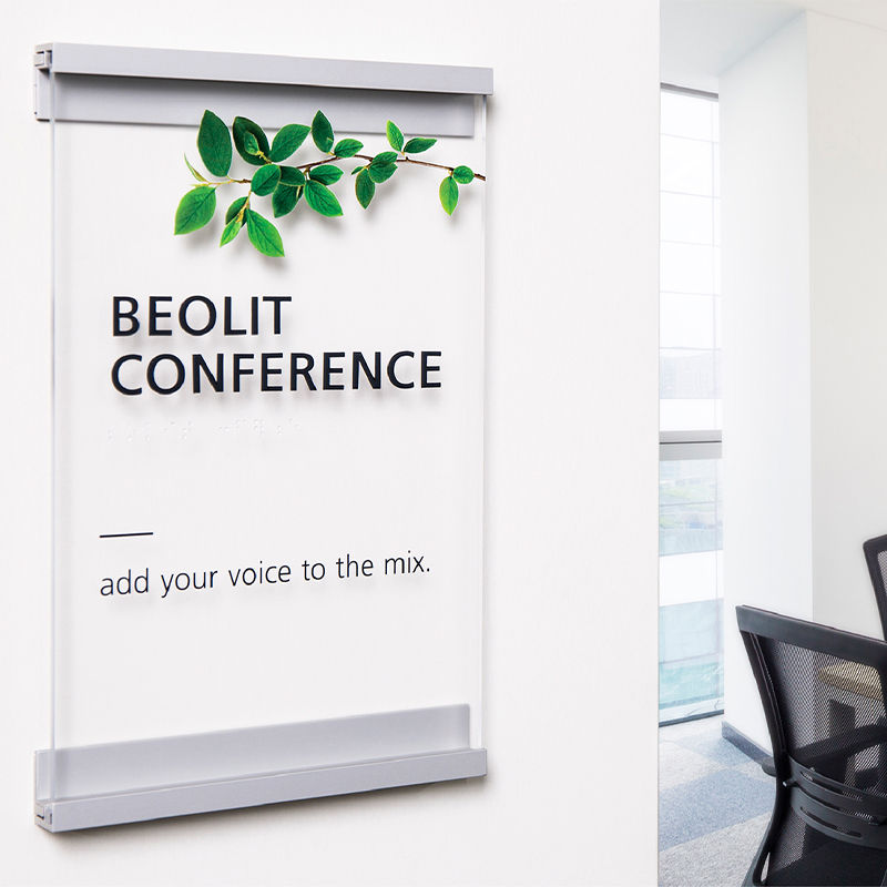 Minimalist metal and glass-look custom conference room sign with a plant-themed design adjacent to doorway