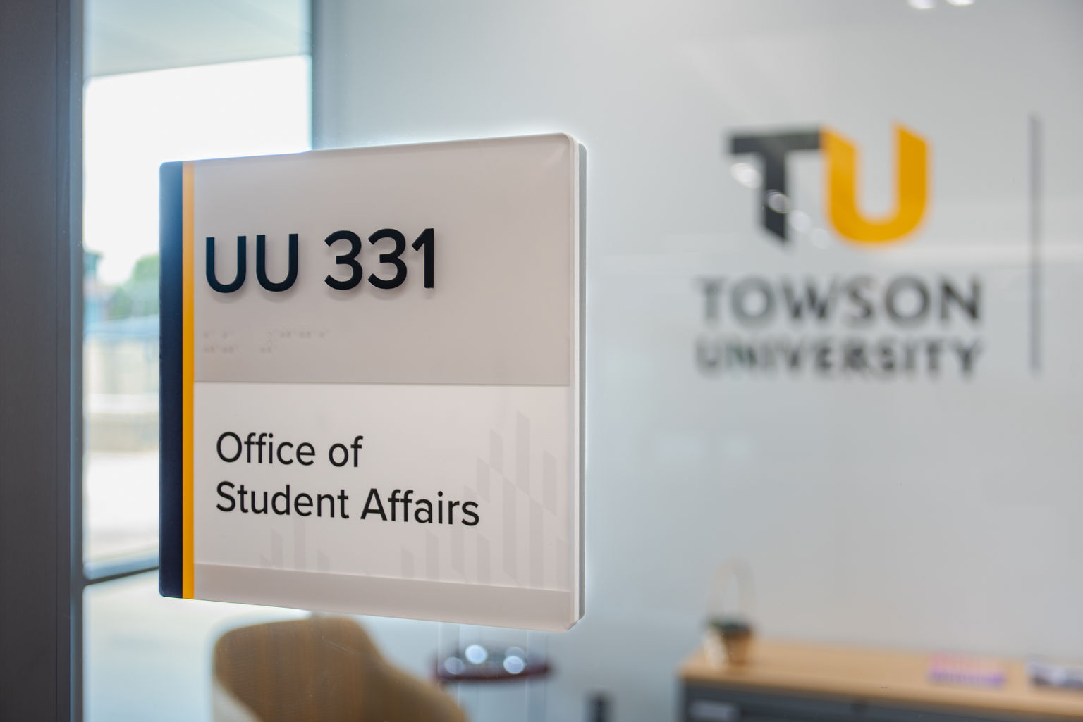 A Vivid room identification sign adhered to a glass partition of a school office.