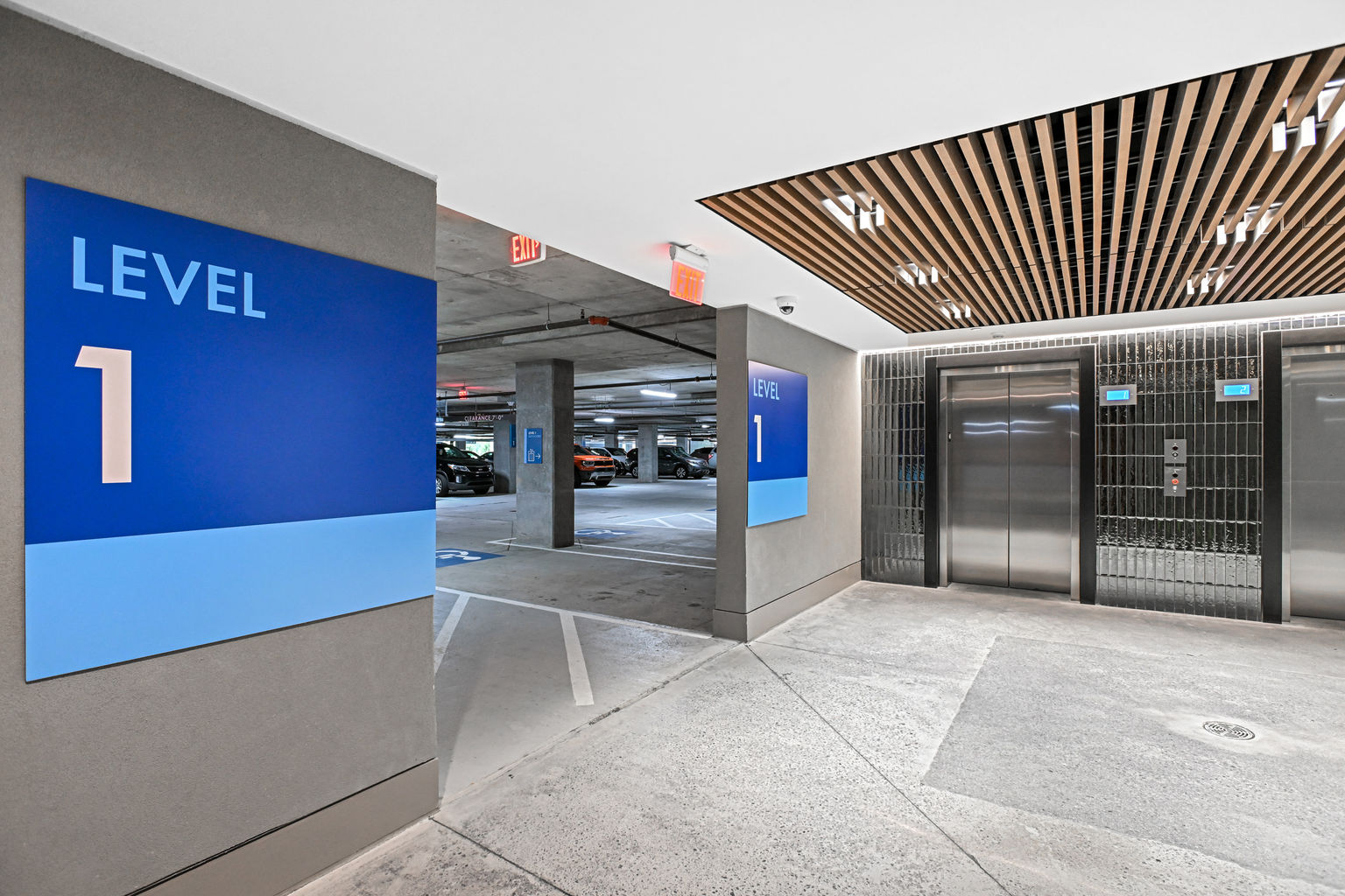 Multiple color-coded level indicators and exterior signage in a parking garage elevator bay that provides wayfinding support