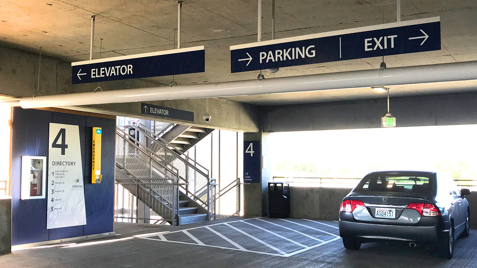 Vehicular wayfinding and parking signage in a parking facility adjacent to an elevator and parked car