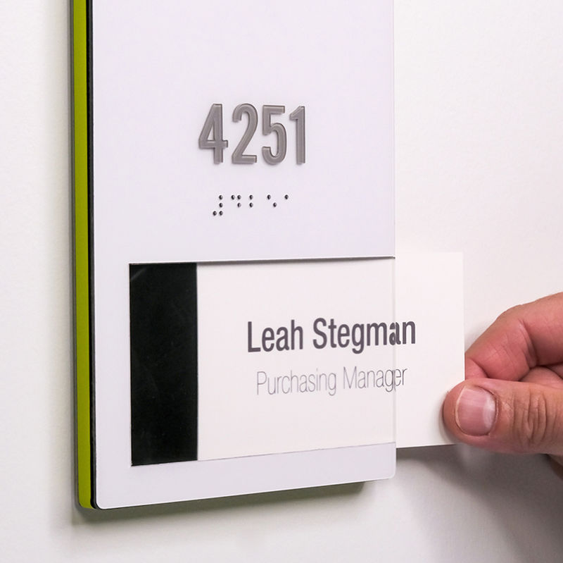 A hand removes the replaceable insert from a branded ADA room ID sign.
