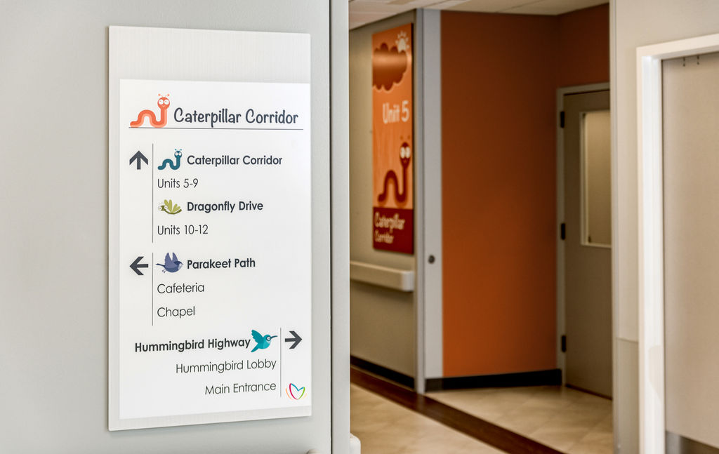 A hospital corridor with custom branded interior directional signs with a playful animal theme.