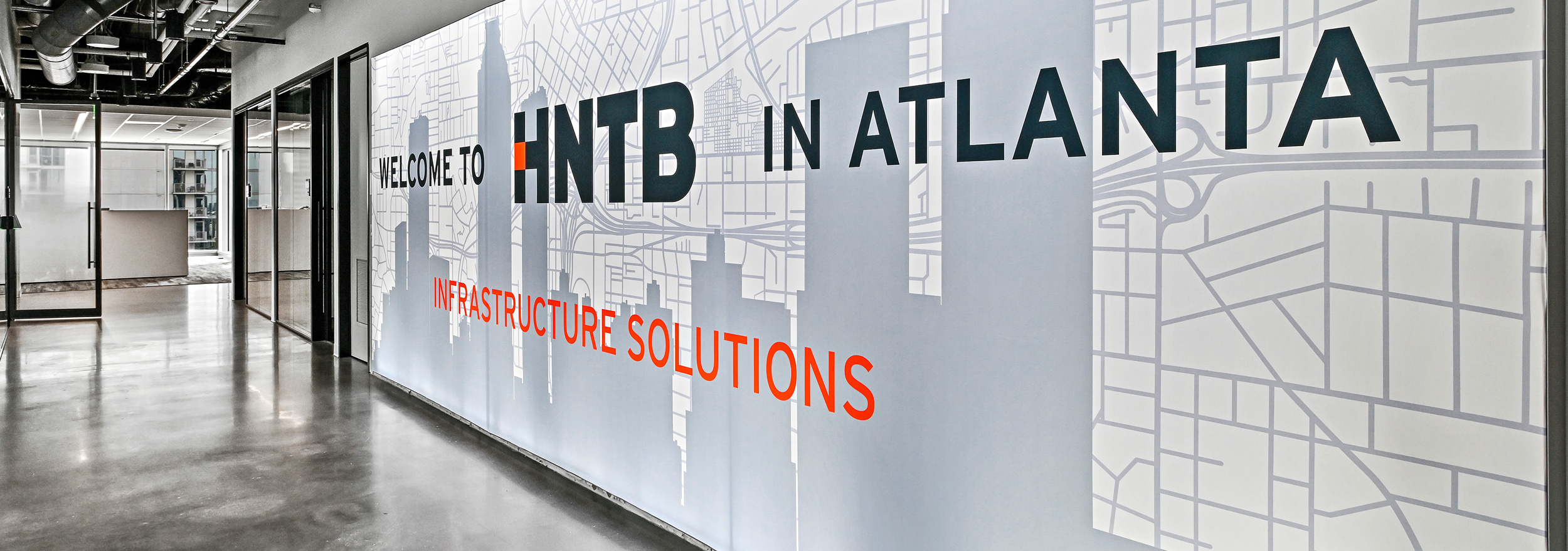 A photo of an wall-to-wall illuminated silicone edge graphic with a custom printed graphic over an Atlanta skyline line drawing.