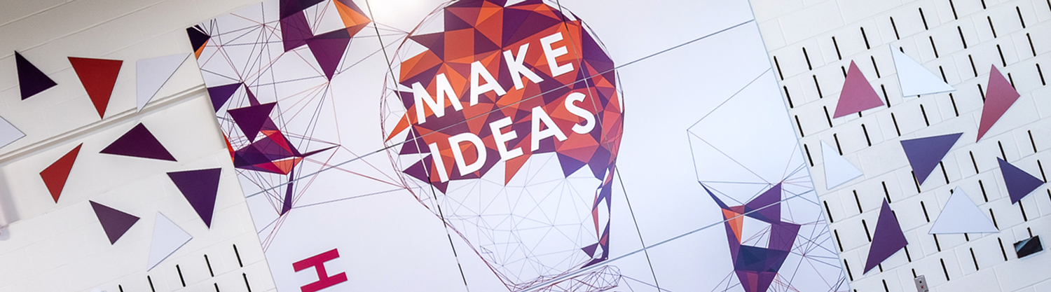 A visually energetic "Make Ideas" graphic panel installation in a professional school maker's space.