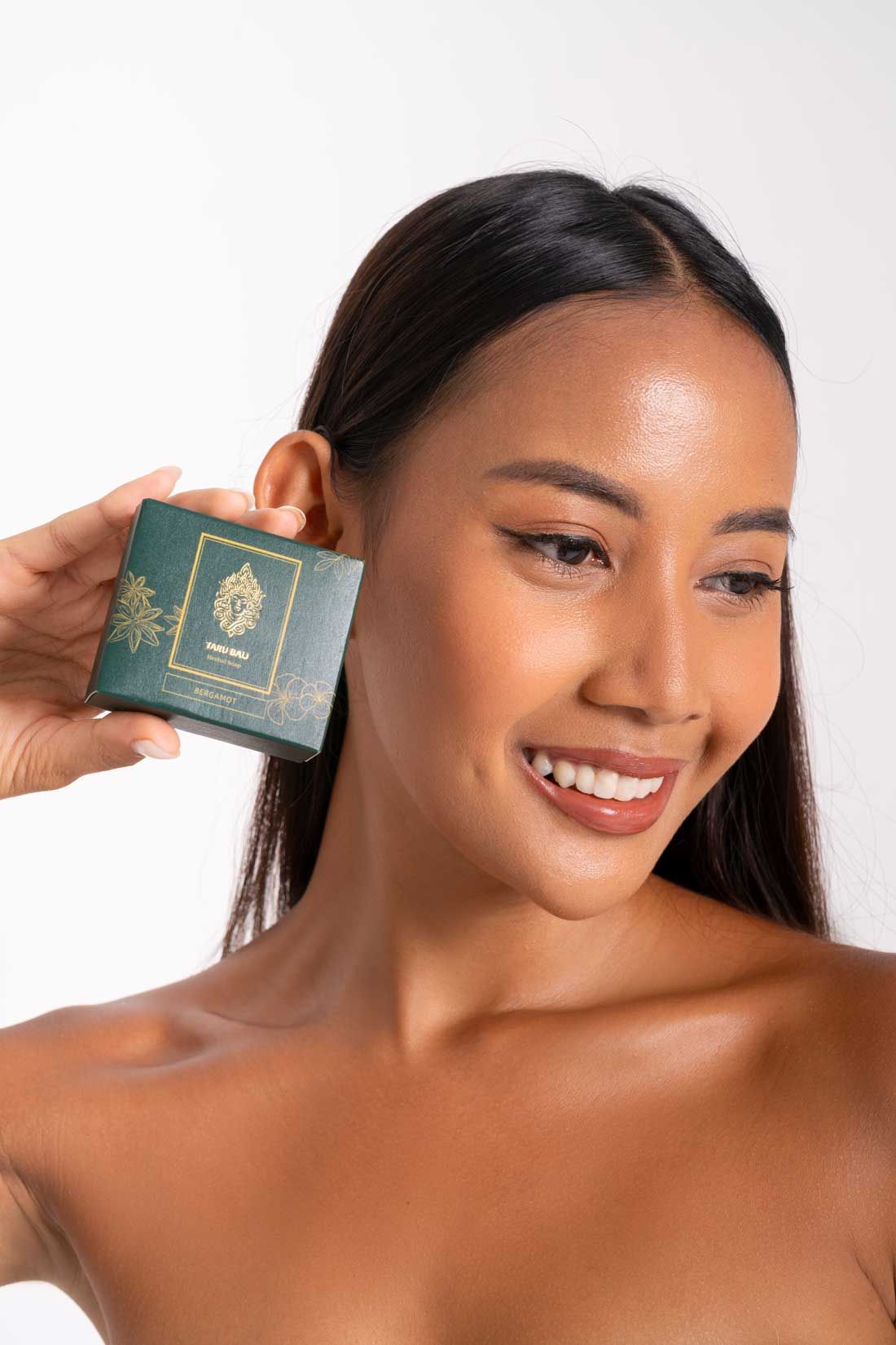 A woman holding the Taru Bali herbal soap, made with 100% natural ingredients