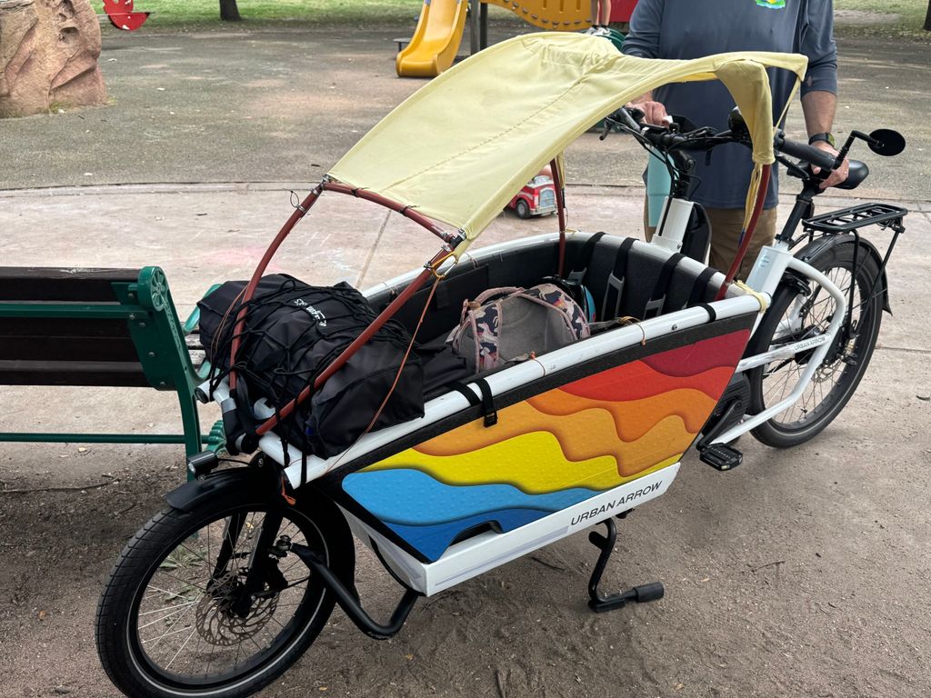 Urban Arrow e-bike with a DIY sunshade and rainbow decals on the bucket.