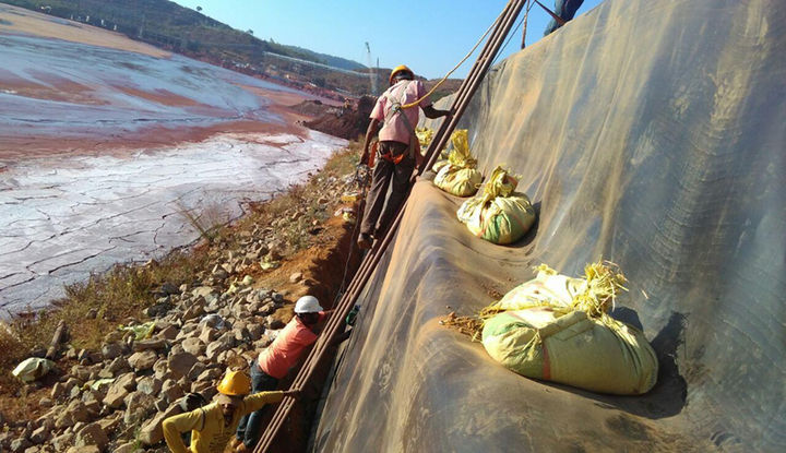 PHOTOGRAPH SHOWING GEOMEMBRANE INSTALLATION OVER THE GABION WALL FACIA