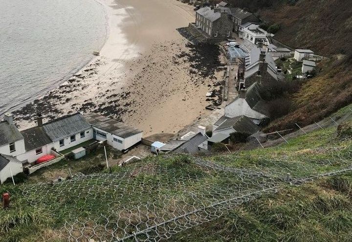 DT rockfall netting secured around a crest rope anchored to the cliff slope.