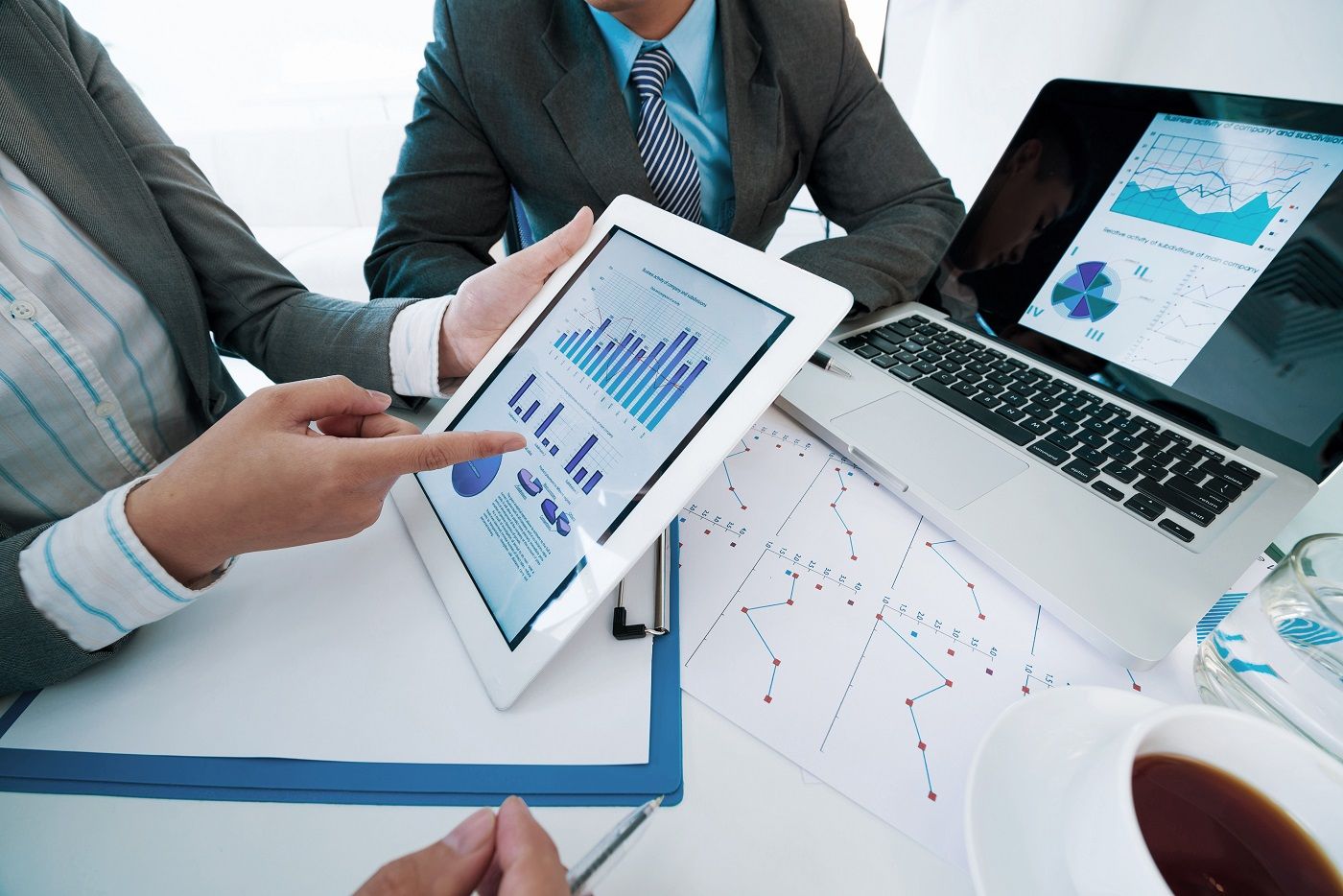 Group of executives discussing business activity graphs on tablet screen