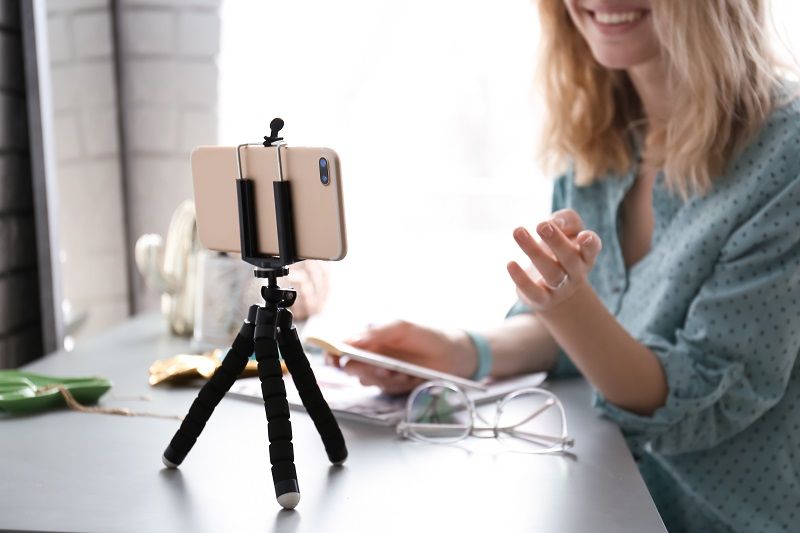 Female blogger recording video at table