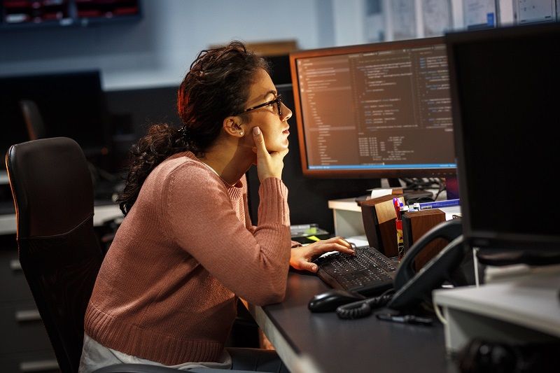 Female programmer working on new project.She working late at night in her office.