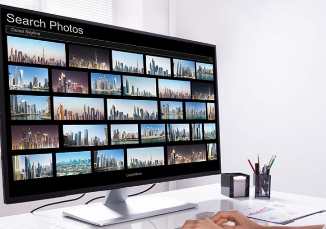 Young Female Editor Searching Photos On Computer At Workplace