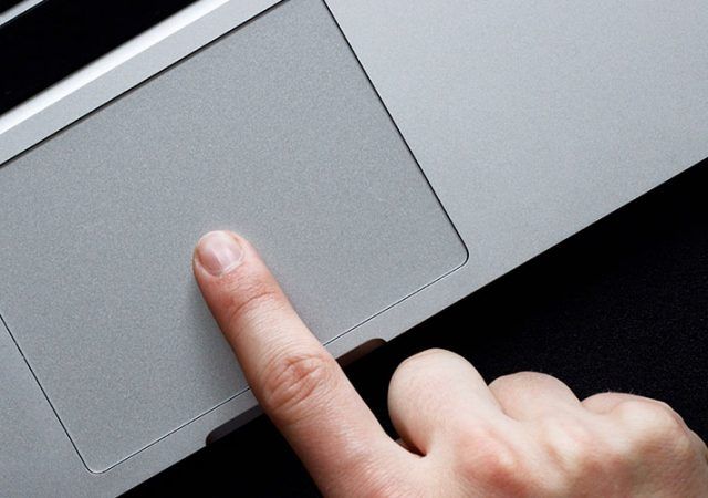 Hand using trackpad on laptop over black background