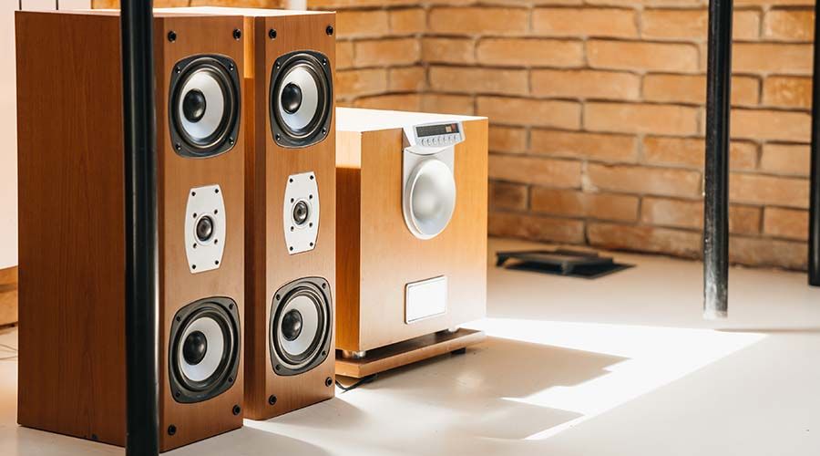 Musical stereo speakers and wooden subwoofer in the interior of a bright room. Musical concept.