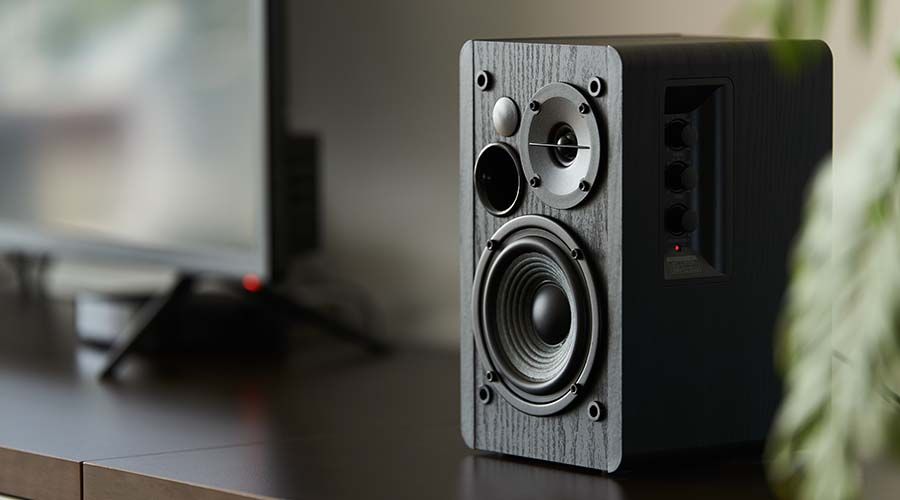 bookshelf speaker with digital TV and set top box on a TV stand