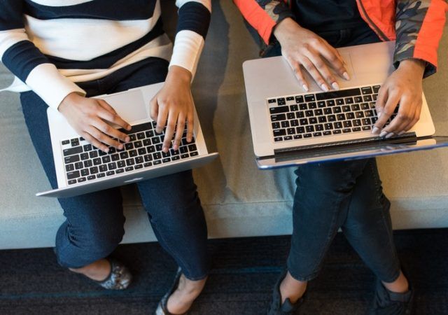 two people holding laptops