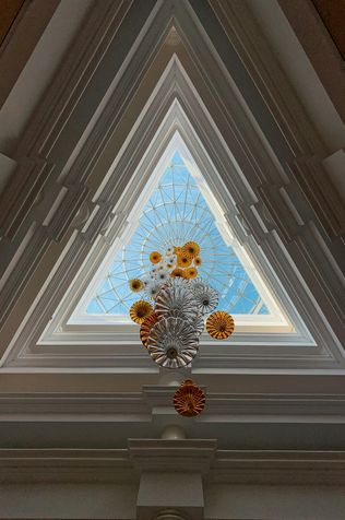 Flowers in front of a triangular window.