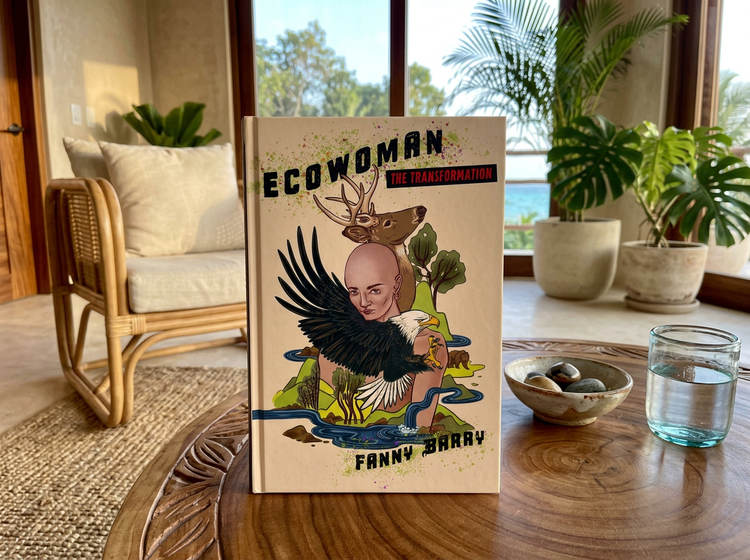 A book titled "Ecowoman: The Transformation" by Fanny Barry sits on a wooden table in a bright, plant-filled room overlooking water A book titled "Ecowoman: The Transformation" by Fanny Barry sits on a wooden table in a bright, plant-filled room overlooking water