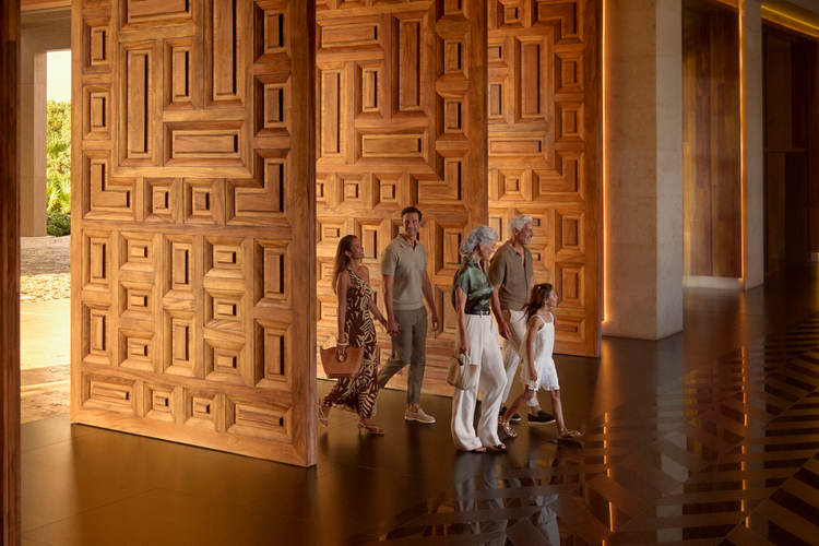 Un grupo de visitantes recorre un espacio interior moderno con grandes puertas de paneles de madera geométricos y pisos pulidos Un grupo de visitantes recorre un espacio interior moderno con grandes puertas de paneles de madera geométricos y pisos pulidos