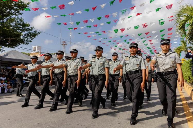 Police officers march in formation down a street decorated with colorful paper flags strung overhead Police officers march in formation down a street decorated with colorful paper flags strung overhead